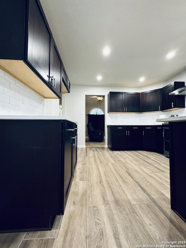 kitchen with a ceiling fan, tasteful backsplash, recessed lighting, light wood-style floors, and light countertops