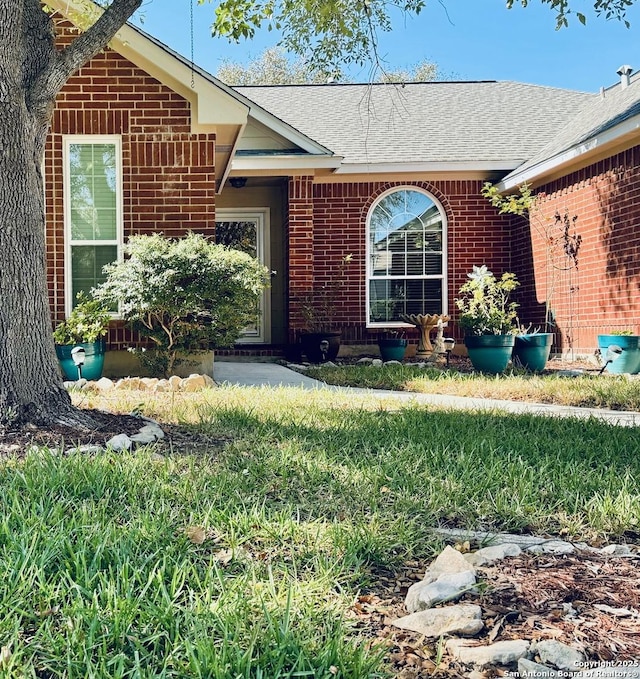 entrance to property with brick siding and roof with shingles