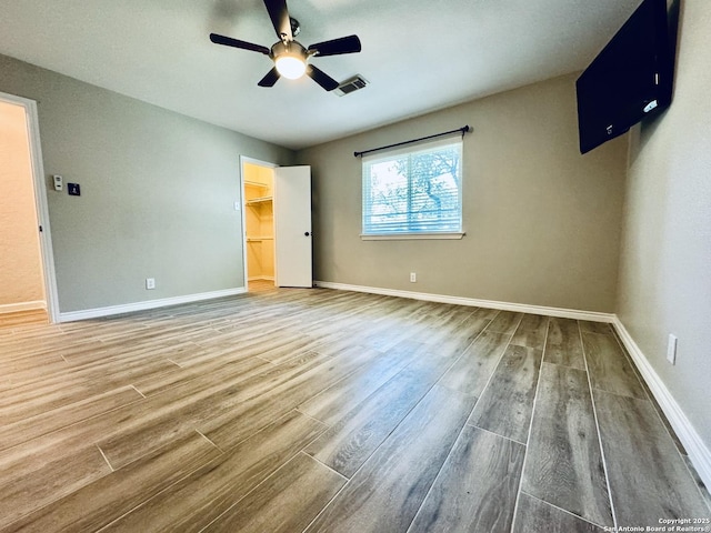 unfurnished bedroom featuring a ceiling fan, wood finished floors, visible vents, and baseboards