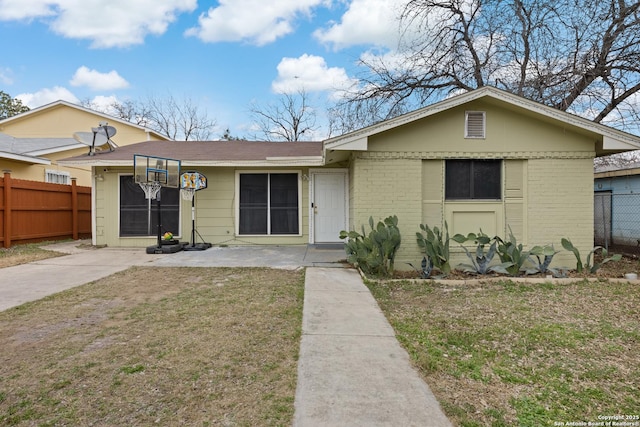 single story home featuring brick siding, a front yard, and fence