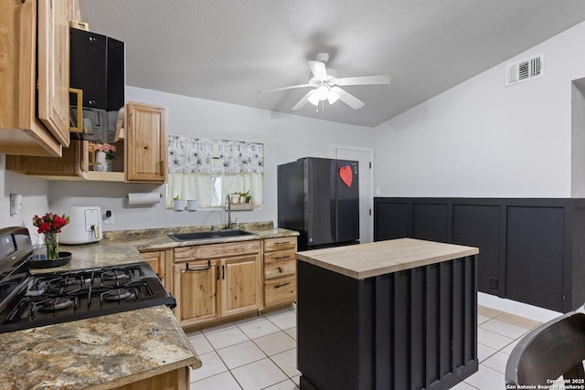 kitchen with light tile patterned floors, butcher block counters, visible vents, a sink, and black appliances