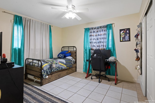 tiled bedroom with a closet, a ceiling fan, and baseboards