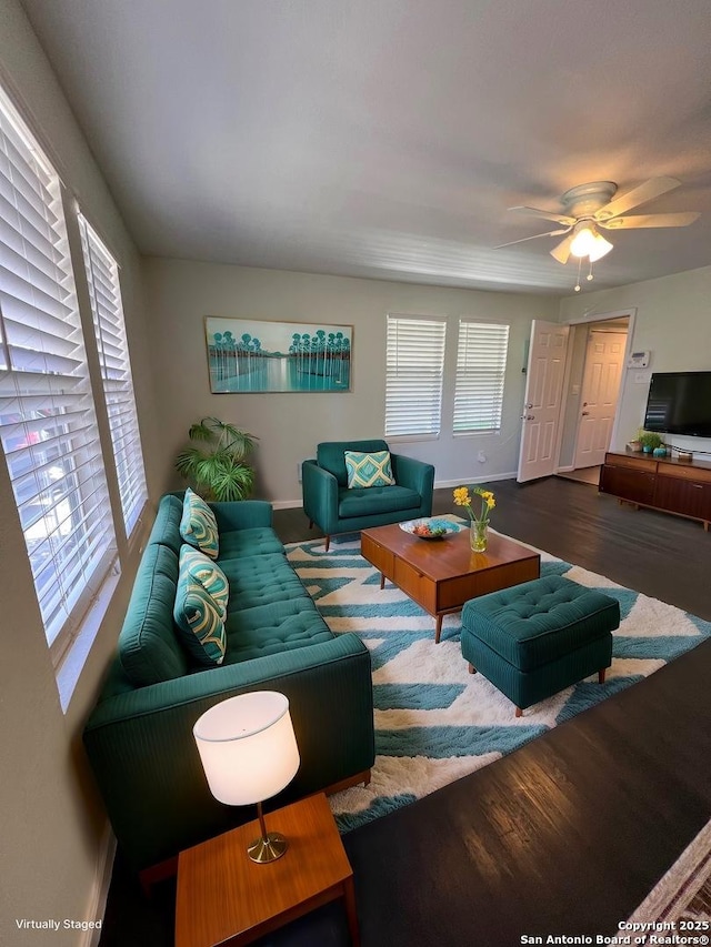 living area with ceiling fan, plenty of natural light, wood finished floors, and baseboards