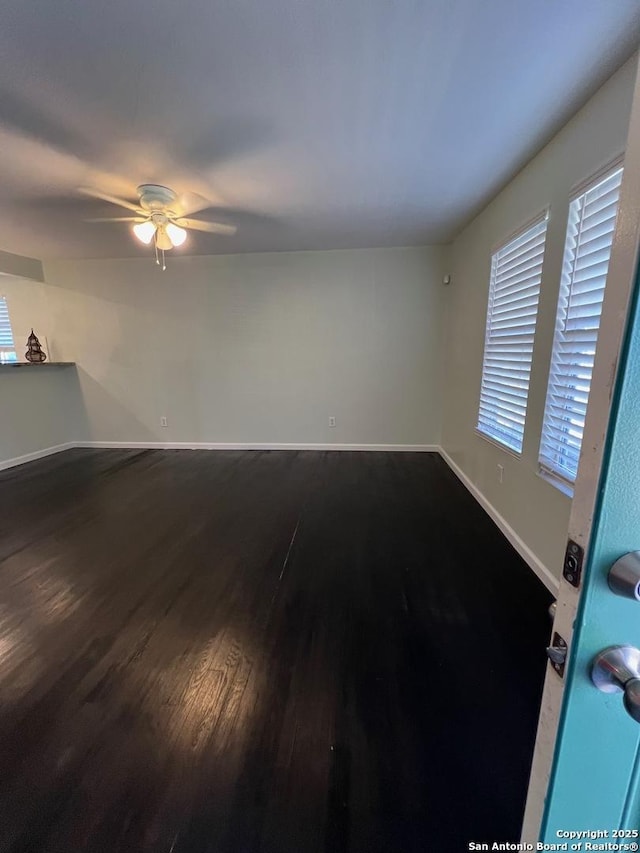 empty room featuring ceiling fan, baseboards, and wood finished floors