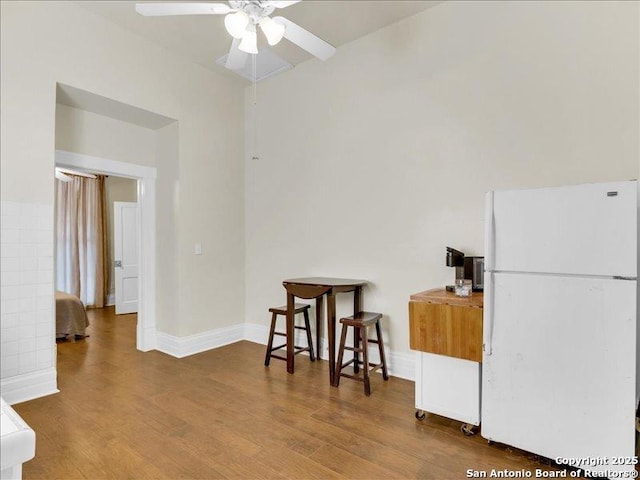 interior space featuring freestanding refrigerator, ceiling fan, baseboards, and wood finished floors