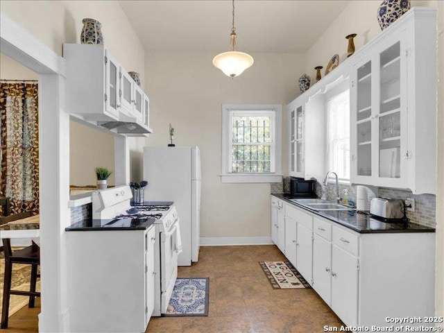 kitchen featuring white appliances, decorative backsplash, dark countertops, glass insert cabinets, and a sink