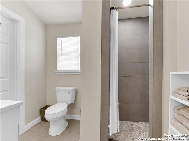 bathroom with tile patterned flooring, baseboards, a tile shower, and toilet