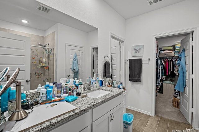 bathroom with wood finish floors, vanity, visible vents, a stall shower, and a walk in closet