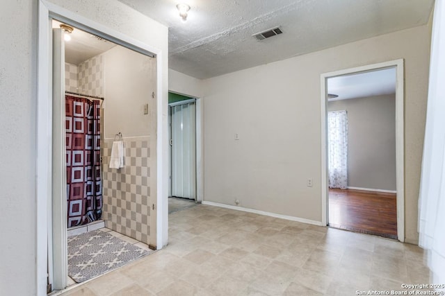 interior space with curtained shower, baseboards, visible vents, and a textured ceiling