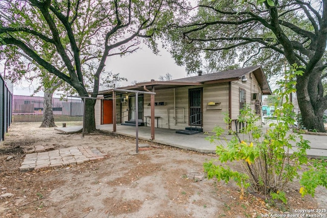 rear view of house featuring entry steps, a patio area, and fence