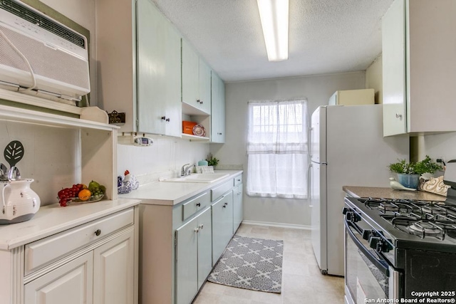 kitchen with a textured ceiling, a sink, light countertops, open shelves, and gas range