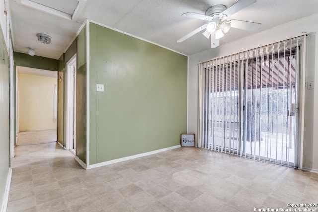 spare room with ceiling fan, ornamental molding, attic access, and baseboards