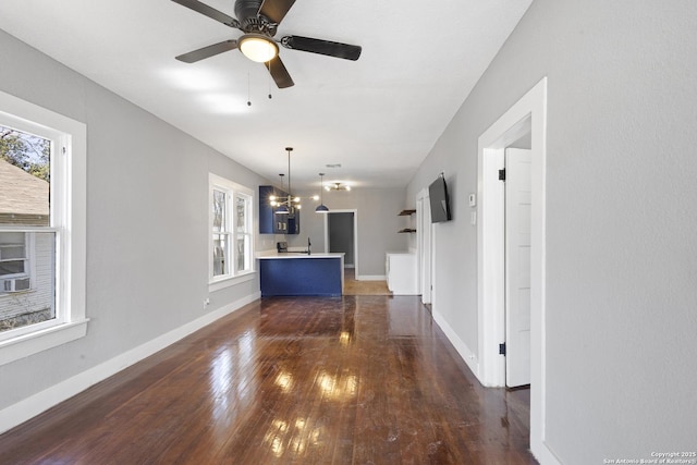 interior space with dark wood-style floors, baseboards, and ceiling fan with notable chandelier