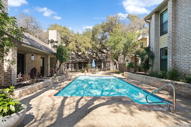 outdoor pool featuring a patio and fence