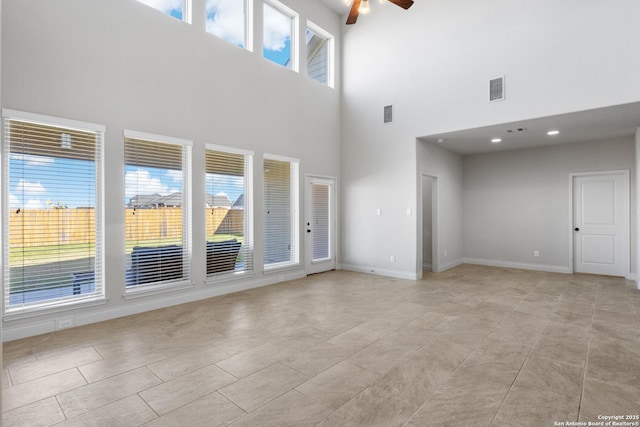 unfurnished living room with a ceiling fan, visible vents, and baseboards