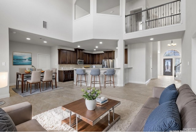 living area featuring baseboards, recessed lighting, visible vents, and a notable chandelier