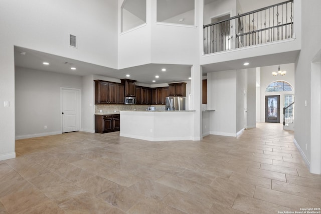 unfurnished living room with baseboards, visible vents, a notable chandelier, and recessed lighting