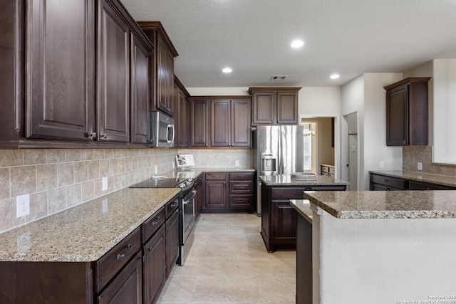 kitchen with stainless steel appliances, dark brown cabinets, and visible vents