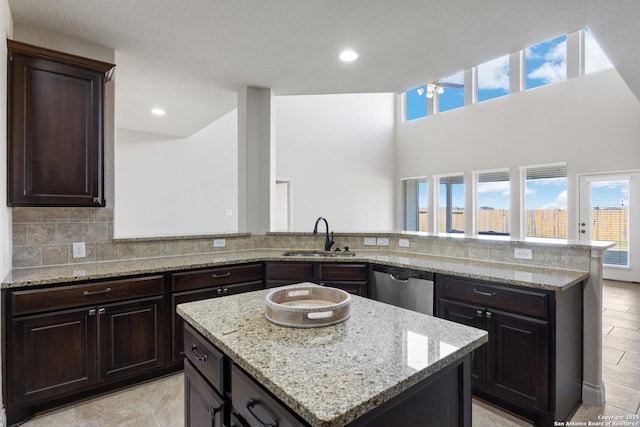 kitchen featuring dishwasher, light stone counters, a sink, and decorative backsplash