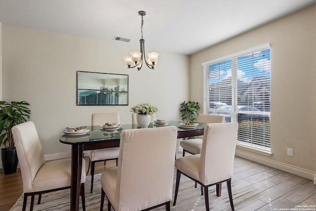 dining area featuring baseboards, light wood-type flooring, visible vents, and a notable chandelier