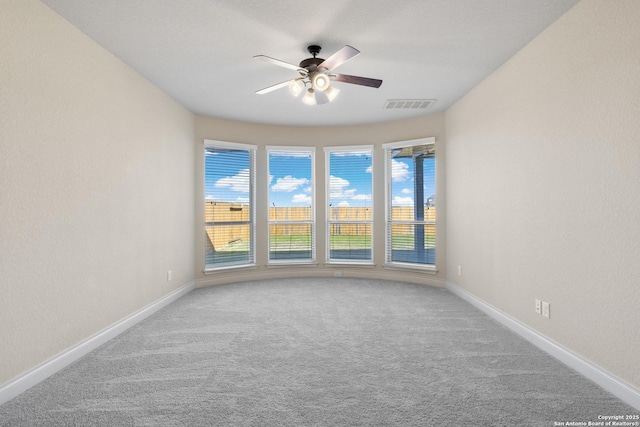 carpeted empty room featuring baseboards, a wealth of natural light, visible vents, and a ceiling fan