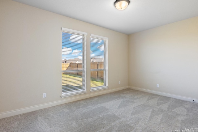 spare room with light carpet and baseboards