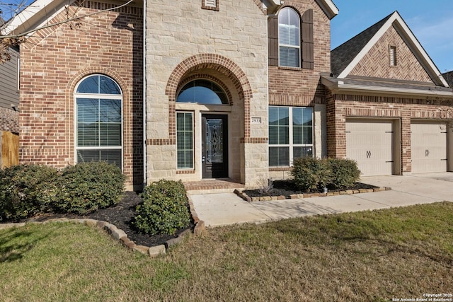 property entrance with a garage, concrete driveway, brick siding, and stone siding