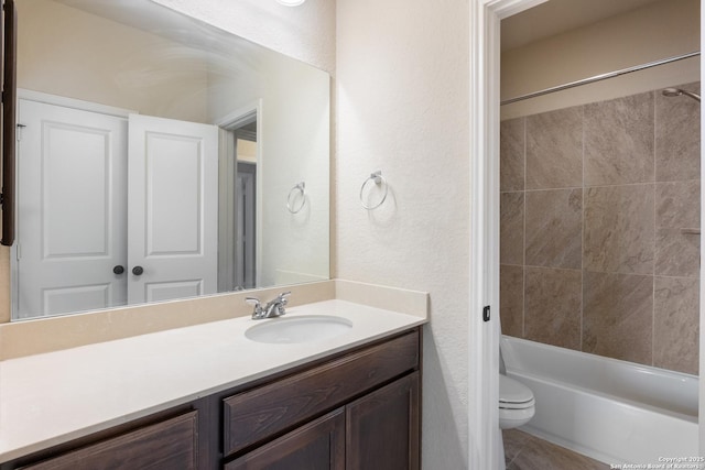 full bathroom featuring a textured wall, bathtub / shower combination, vanity, and toilet