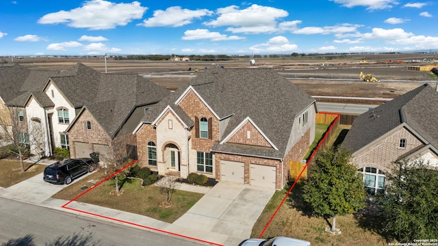 view of front of house featuring a shingled roof, brick siding, and driveway