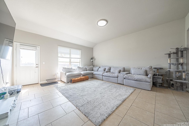 living room featuring vaulted ceiling, light tile patterned flooring, and baseboards