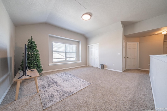 unfurnished room featuring lofted ceiling, carpet floors, a textured ceiling, and baseboards