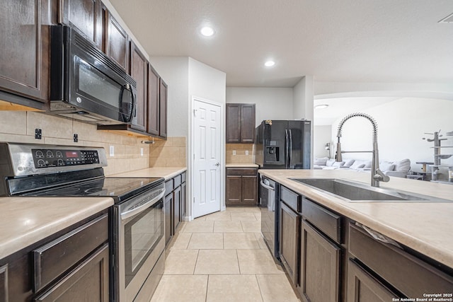 kitchen with light countertops, a sink, black appliances, and dark brown cabinets