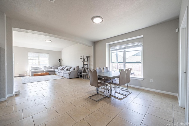 dining room with light tile patterned floors, plenty of natural light, baseboards, and a textured ceiling