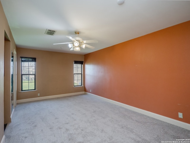 empty room with carpet floors, visible vents, and baseboards