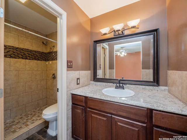 bathroom featuring a tile shower, toilet, tile walls, and vanity