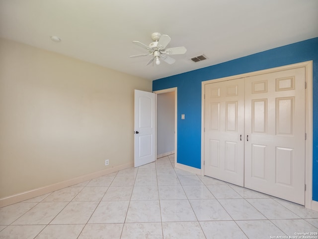 unfurnished bedroom with light tile patterned flooring, a ceiling fan, visible vents, baseboards, and a closet