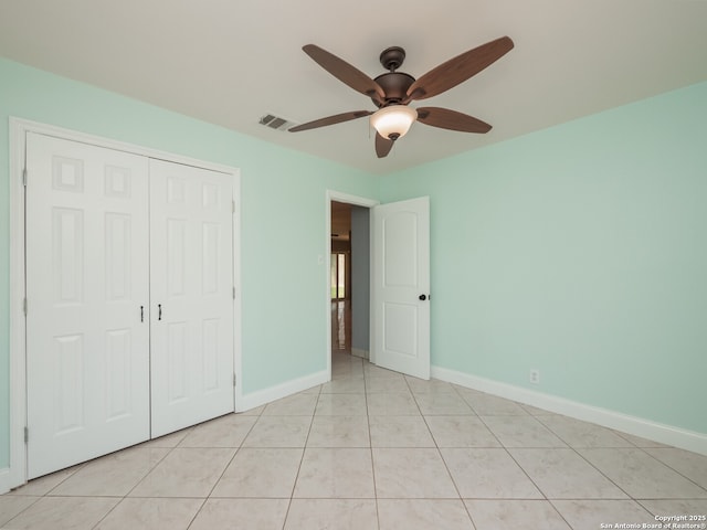 unfurnished bedroom featuring light tile patterned floors, a closet, visible vents, a ceiling fan, and baseboards