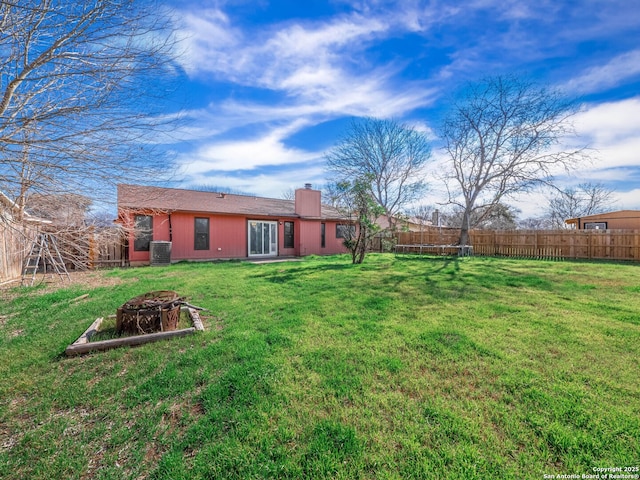 view of yard with an outdoor fire pit, fence, and central air condition unit