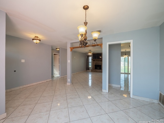 empty room featuring light tile patterned floors, baseboards, visible vents, a brick fireplace, and ceiling fan with notable chandelier