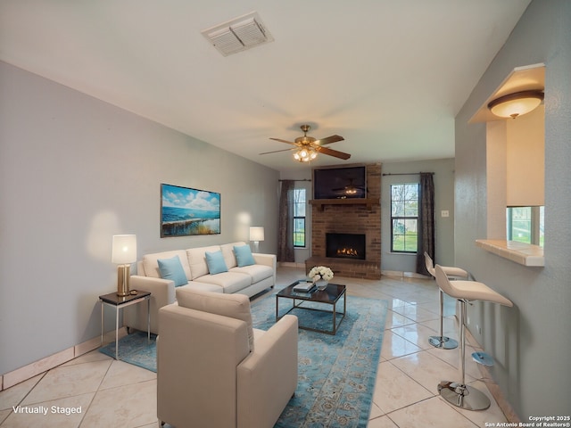 living area featuring ceiling fan, visible vents, a fireplace, and light tile patterned floors