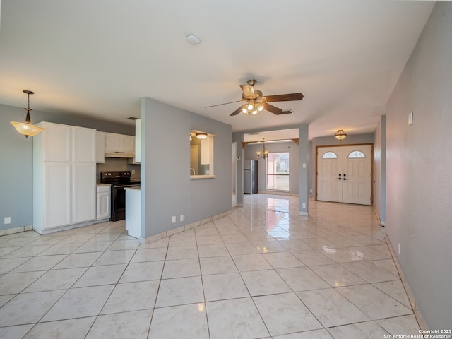 unfurnished living room with light tile patterned floors, ceiling fan with notable chandelier, and baseboards