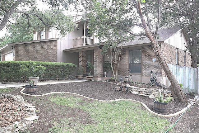 back of property with a garage, brick siding, fence, and a balcony