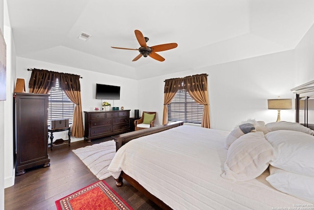 bedroom featuring wood-type flooring, multiple windows, visible vents, and a raised ceiling