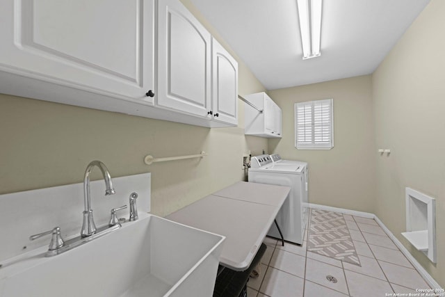 clothes washing area featuring cabinet space, light tile patterned floors, baseboards, washing machine and clothes dryer, and a sink