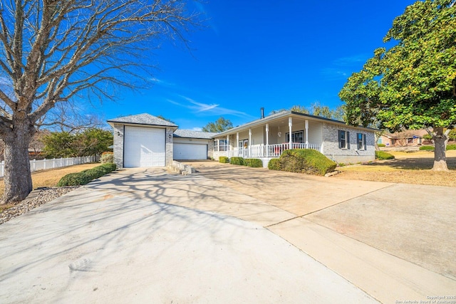 ranch-style home with a garage, covered porch, driveway, and fence