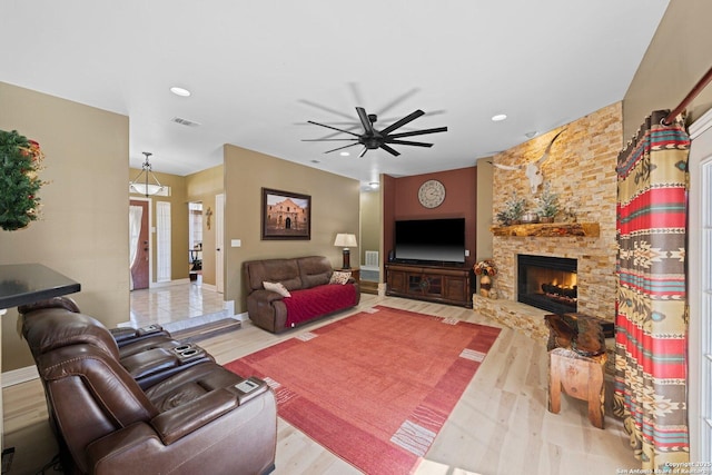 living area featuring a stone fireplace, recessed lighting, wood finished floors, visible vents, and a ceiling fan