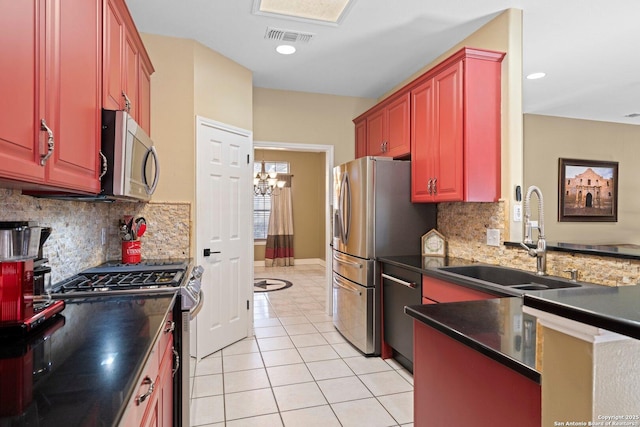 kitchen featuring dark countertops, visible vents, appliances with stainless steel finishes, light tile patterned flooring, and a sink