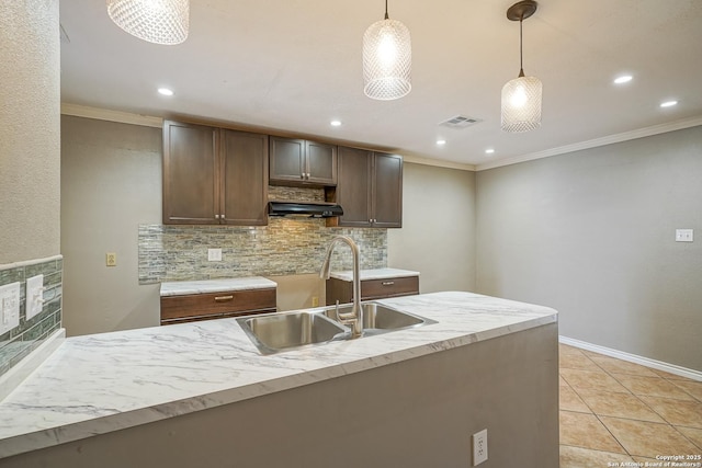 kitchen featuring visible vents, decorative backsplash, ornamental molding, decorative light fixtures, and a sink