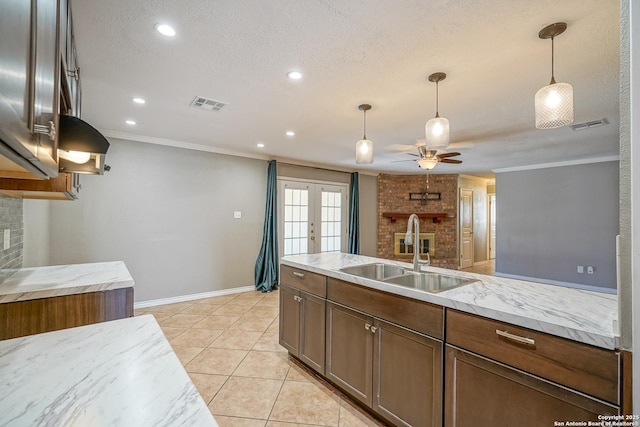 kitchen featuring french doors, crown molding, visible vents, hanging light fixtures, and a sink