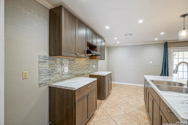 kitchen with visible vents, decorative backsplash, ornamental molding, light countertops, and a sink